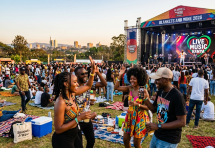 A vibrant outdoor music festival crowd laughing and dancing on picnic blankets during the daytime at Blankets and Wine 2026 in Nairobi, Kenya, with a live music stage and city skyline in the background.